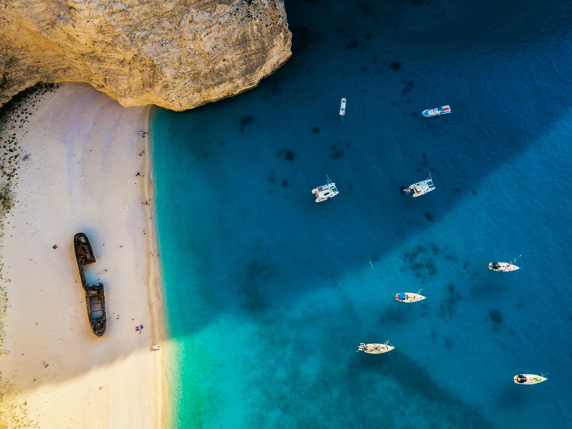 Aerial view of a secluded Mediterranean beach and boats in clear blue water