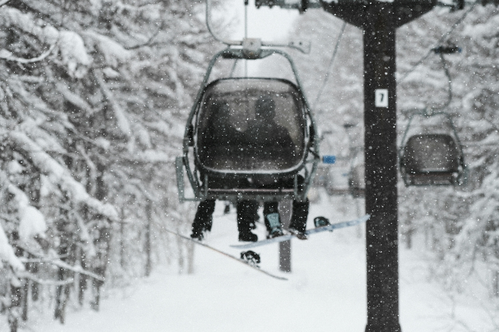 Skiers and snowboarders riding a chairlift above the Alps